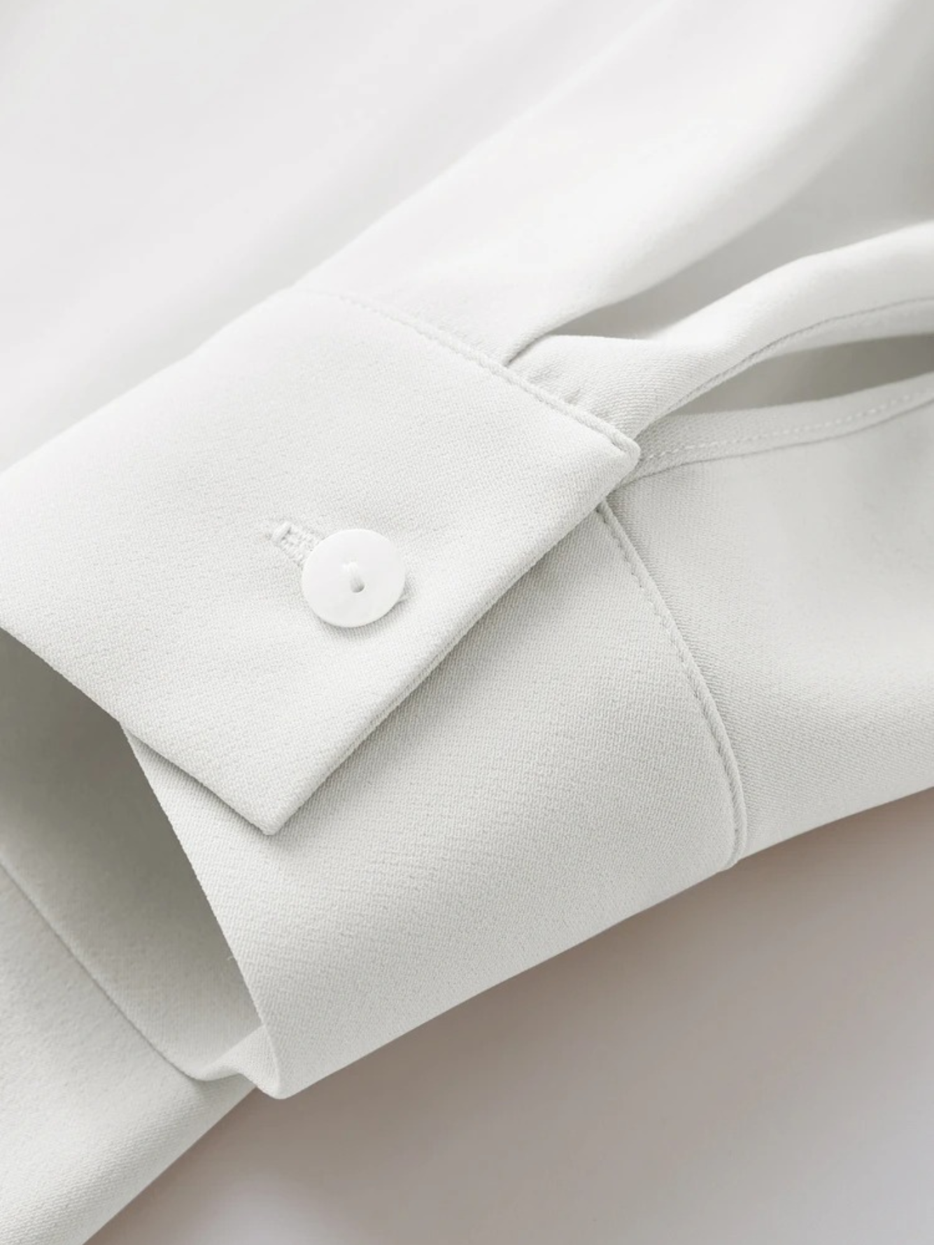 Cuff detail with button on white blouse sleeve