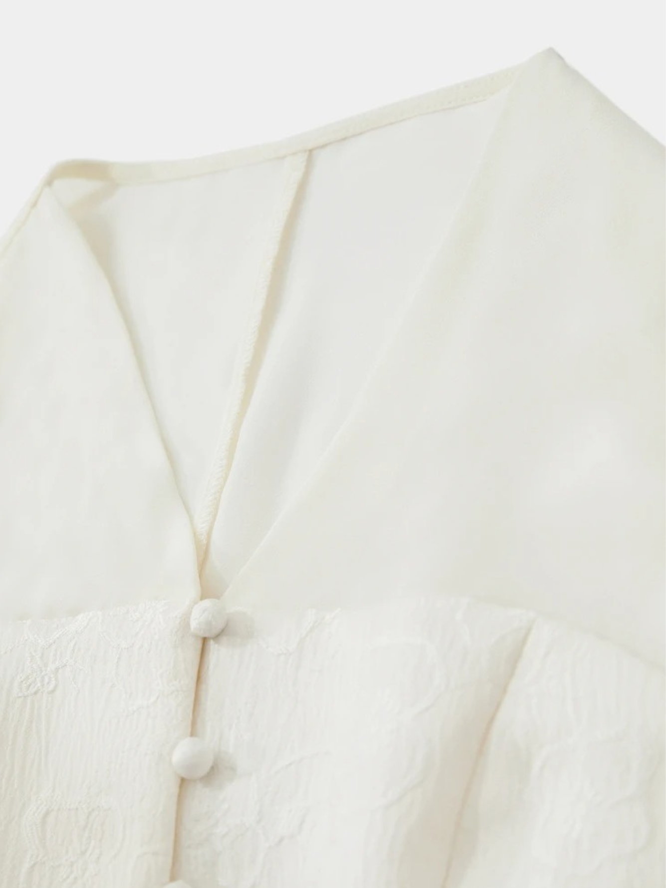 Close-up of front buttons and neckline on cream blouse