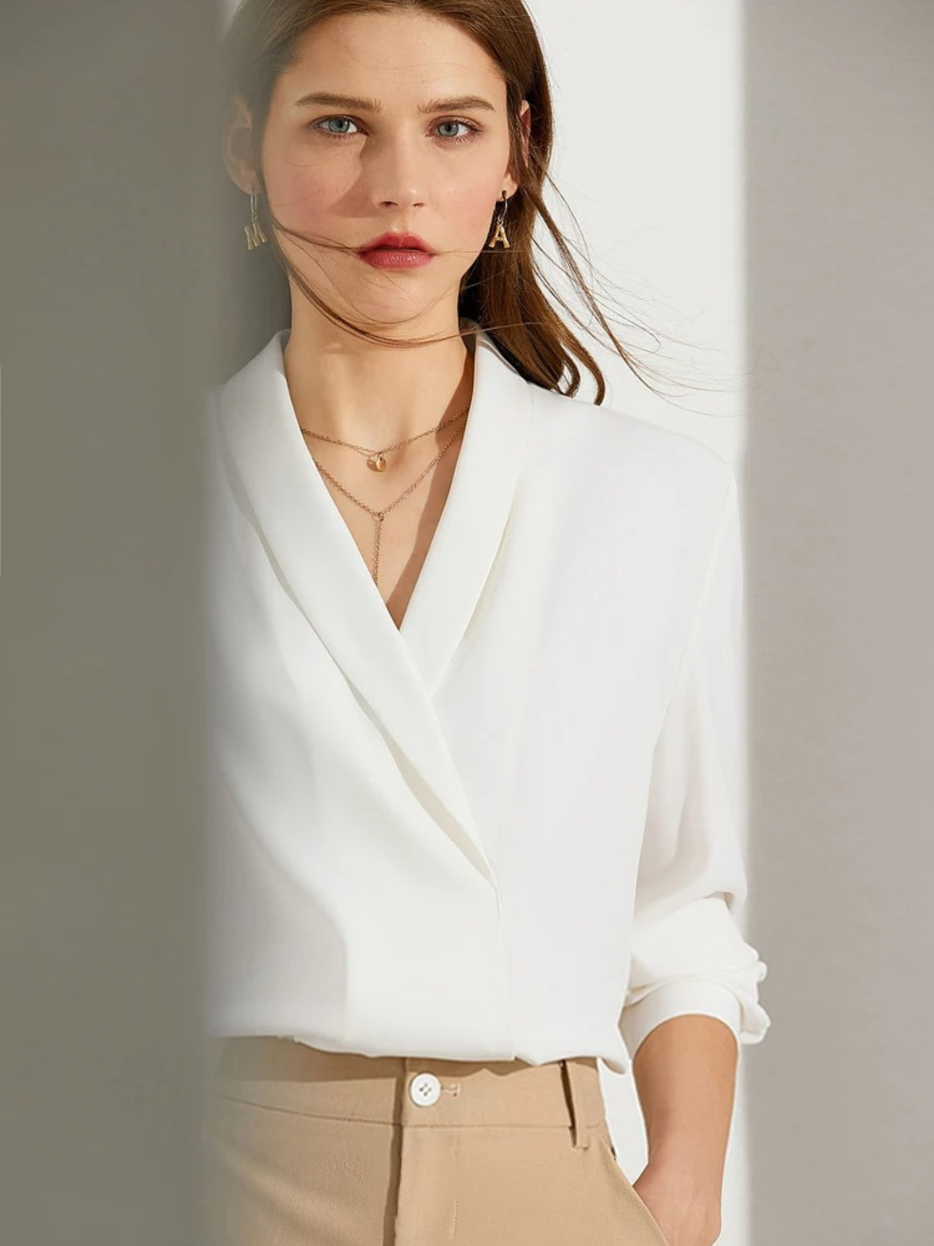 Close-up of white blouse with draped neckline and rolled sleeves