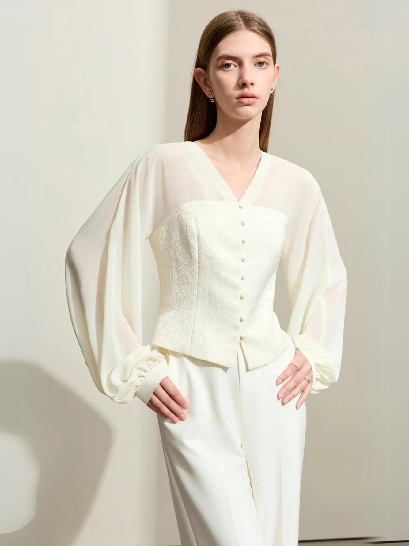 Front view of cream blouse with voluminous sleeves and fitted waist