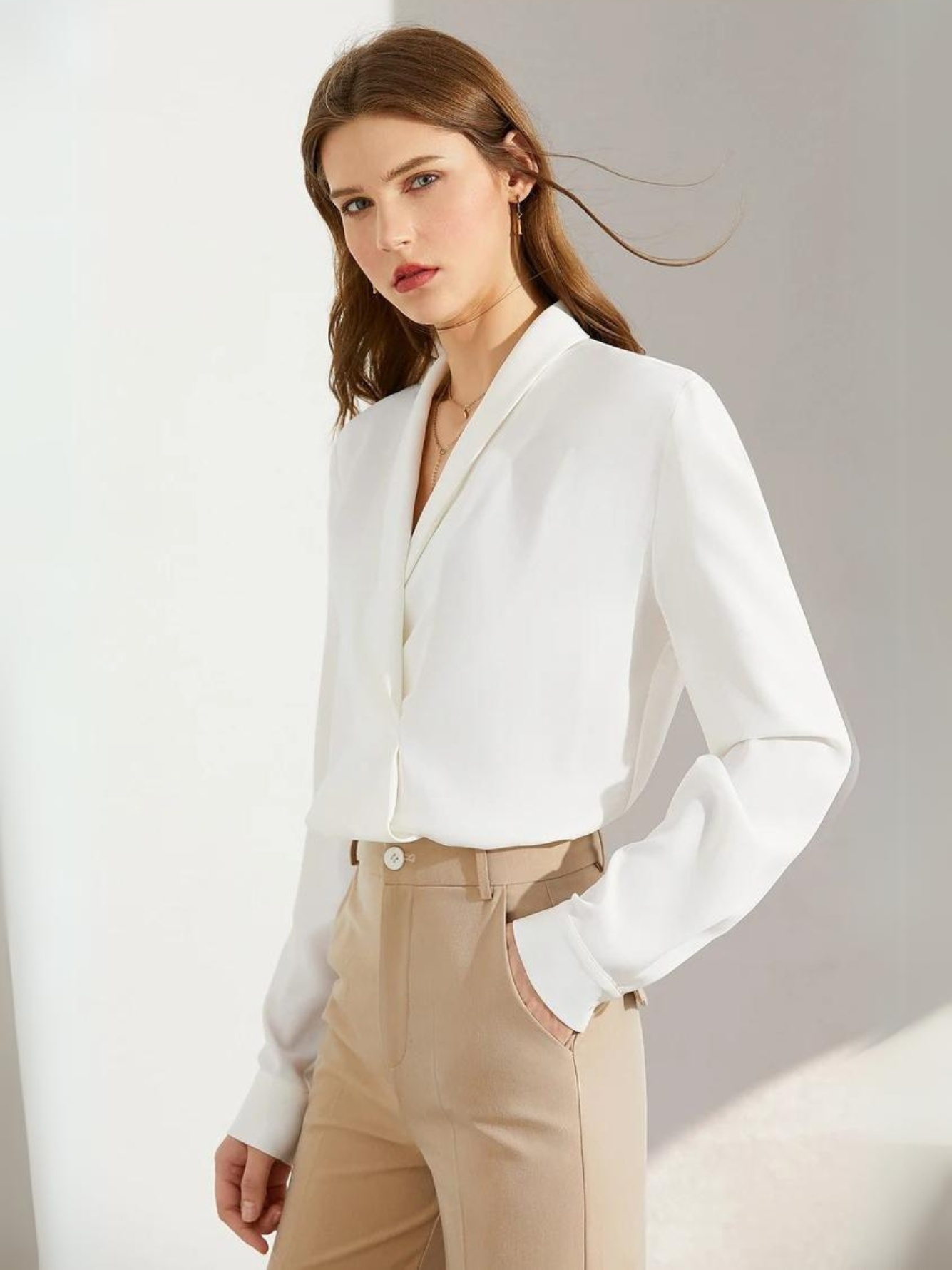 Side view of woman in white blouse with hands in pockets