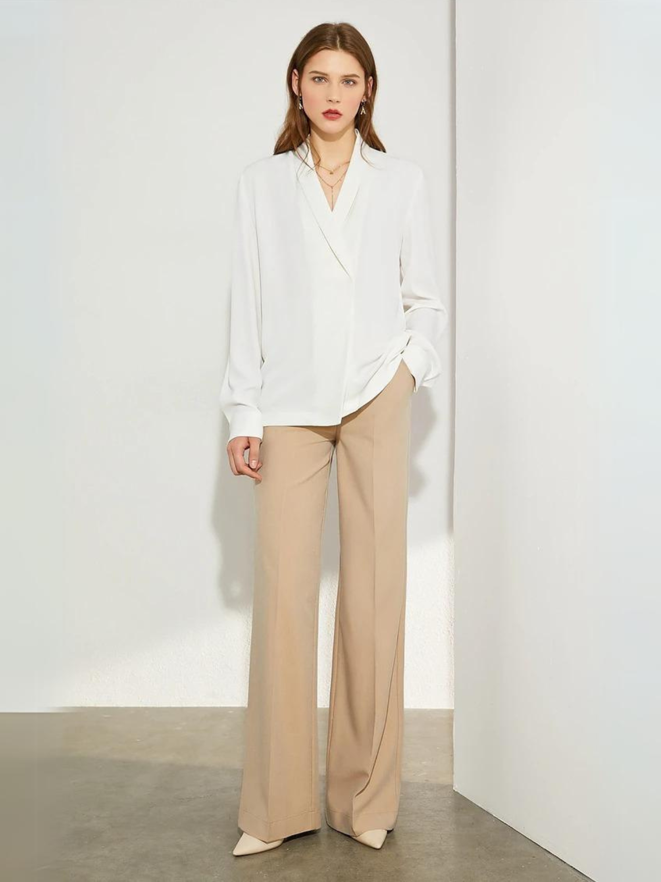 Woman facing forward in white blouse and beige trousers
