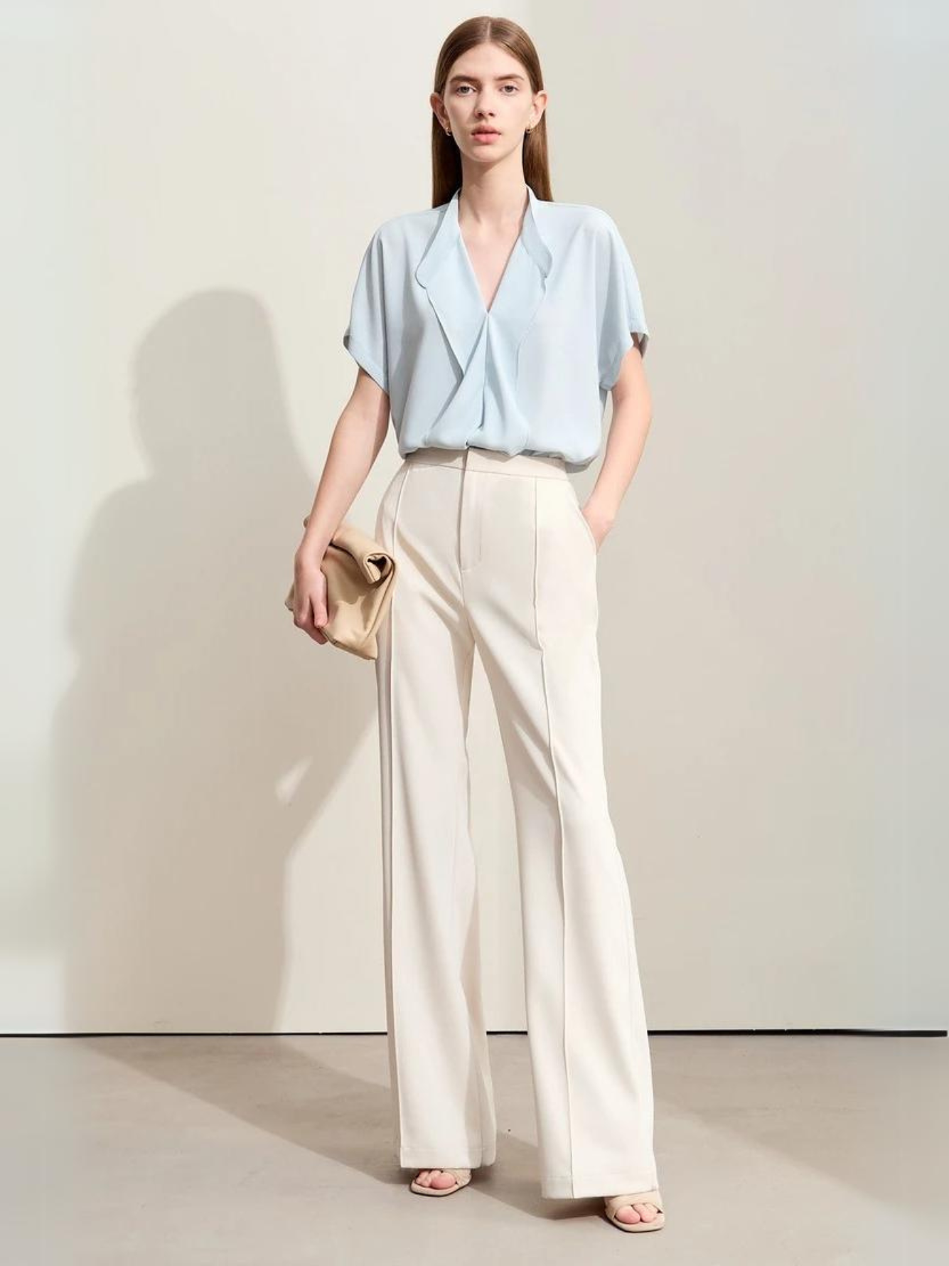 Woman in light blue blouse and wide-leg white trousers