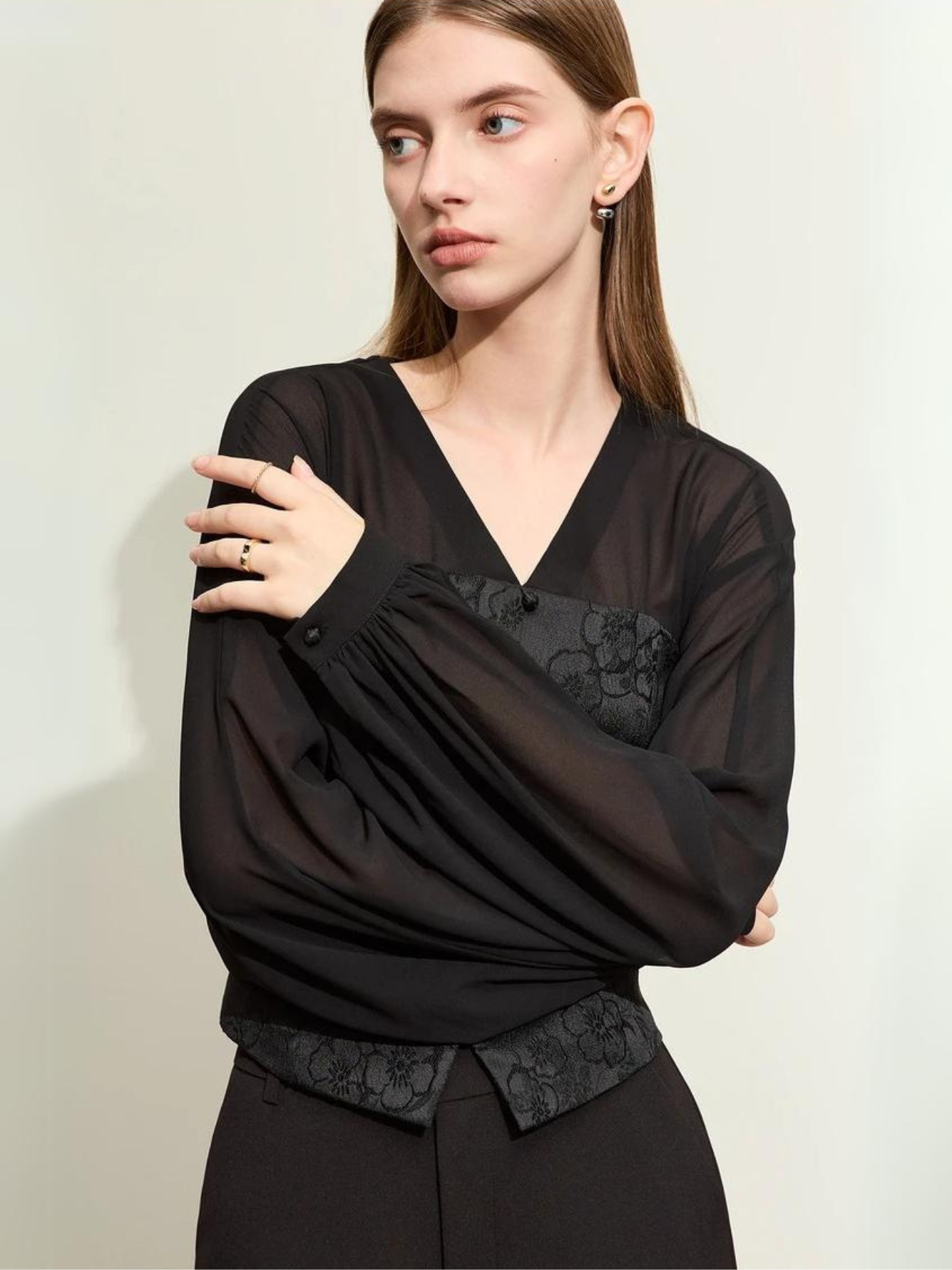 Woman in black blouse with embossed vest and wide-leg trousers