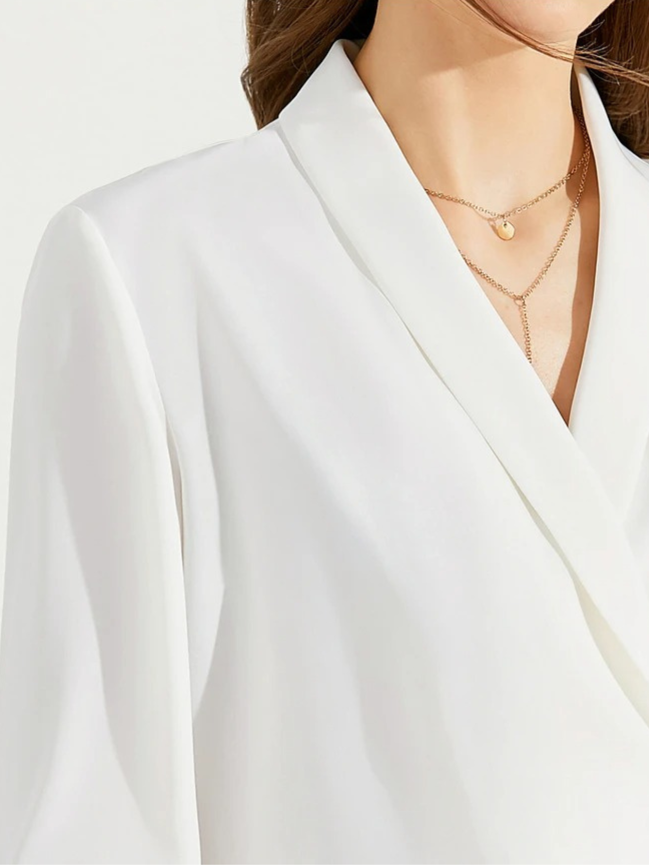 Model standing in sunlight wearing white V-neck blouse