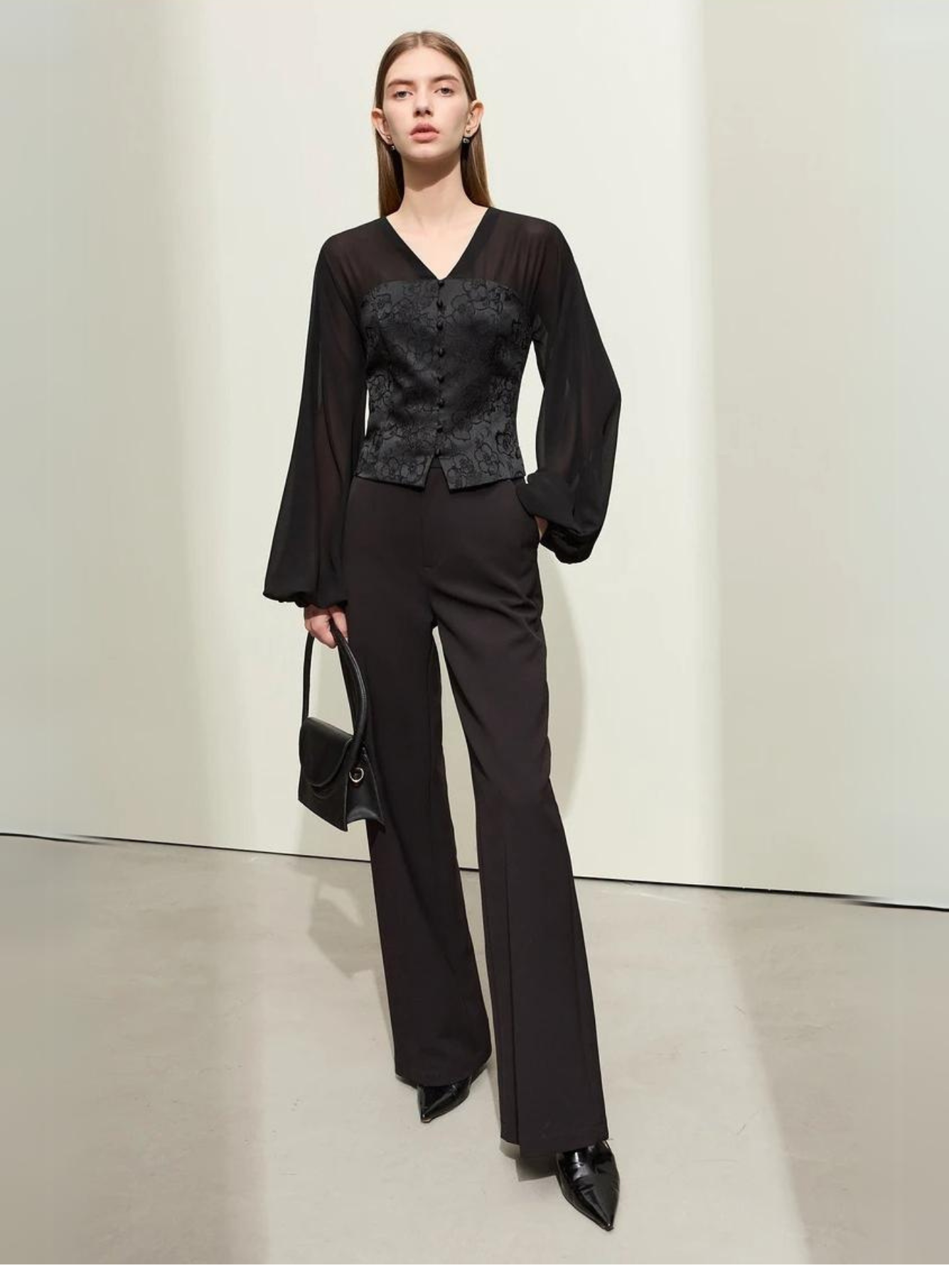 Black blouse with V-neck and wrapped look, arms crossed