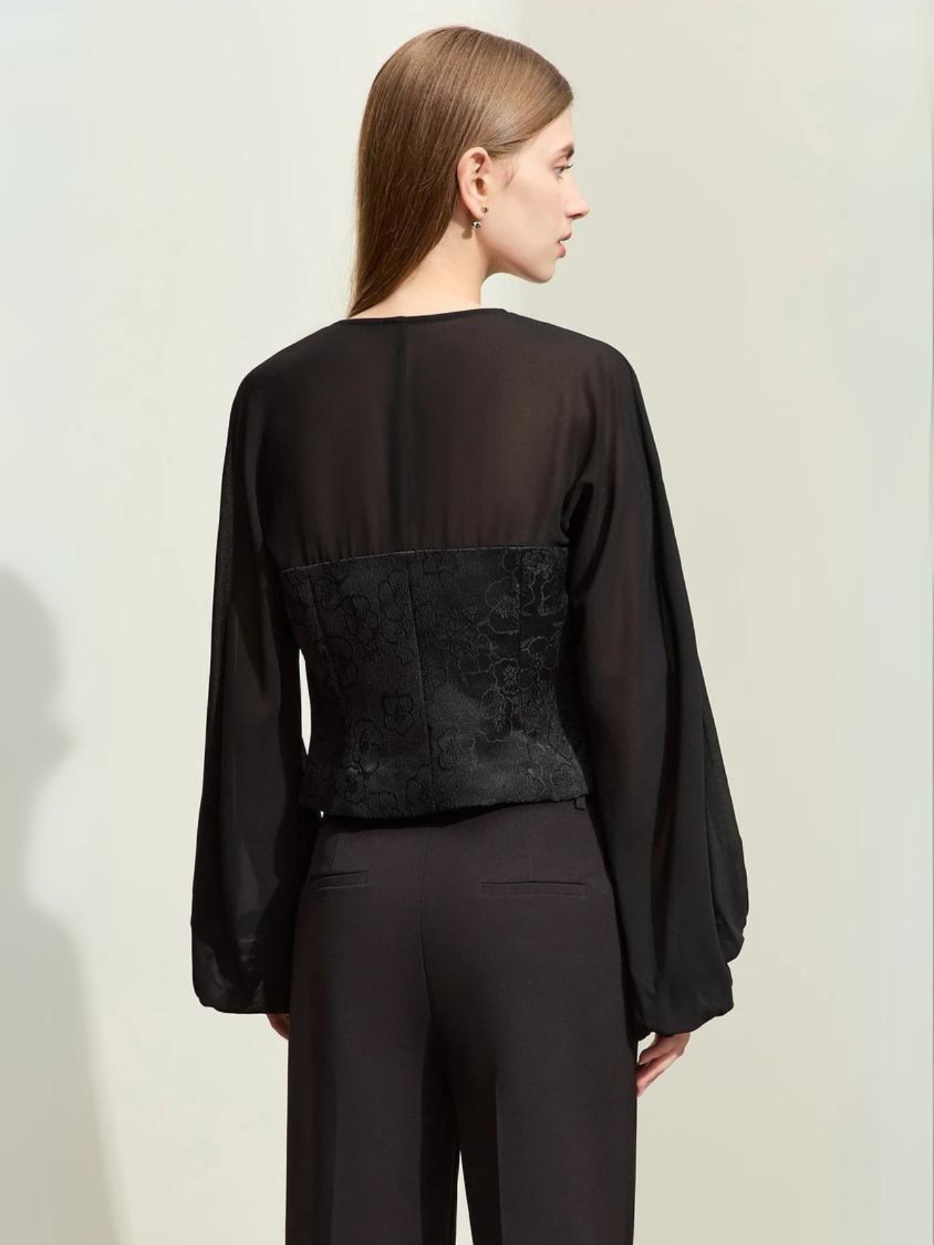 Model walking in black blouse and trousers holding handbag
