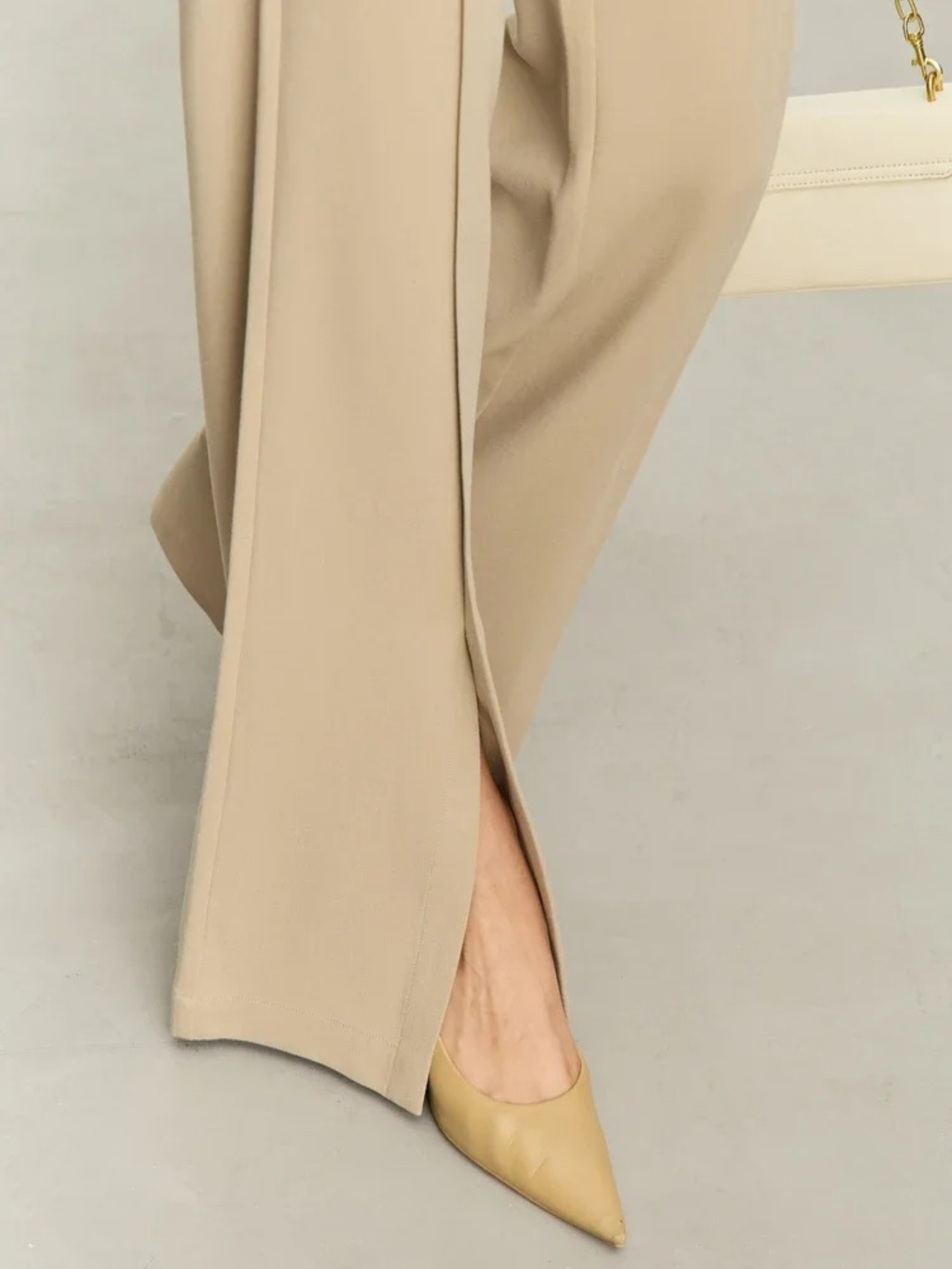 Close up of the hem of tailored, pleated, high waisted pants with slits at the hem