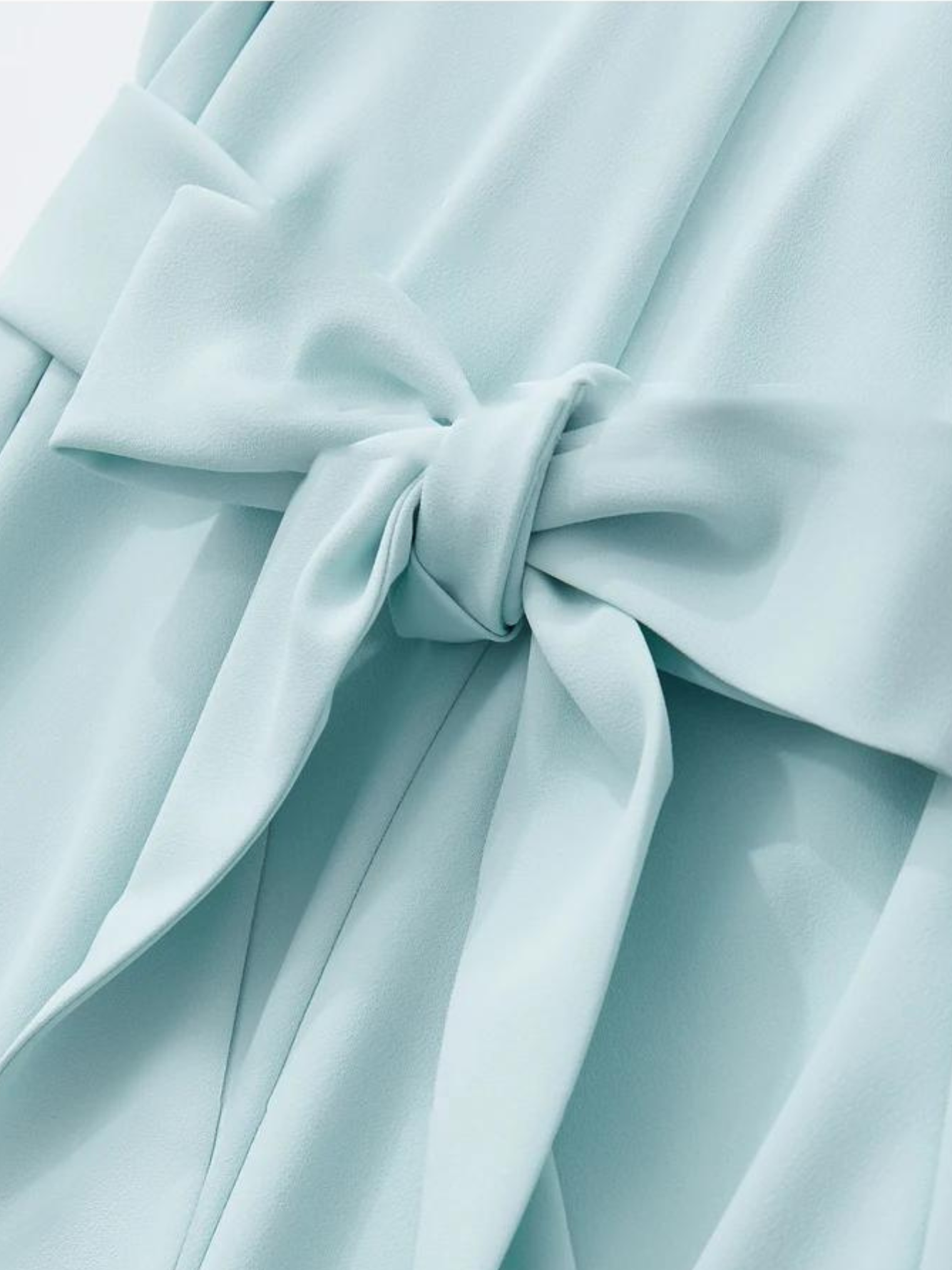 A close up of the bow detail of a baby blue dress.
