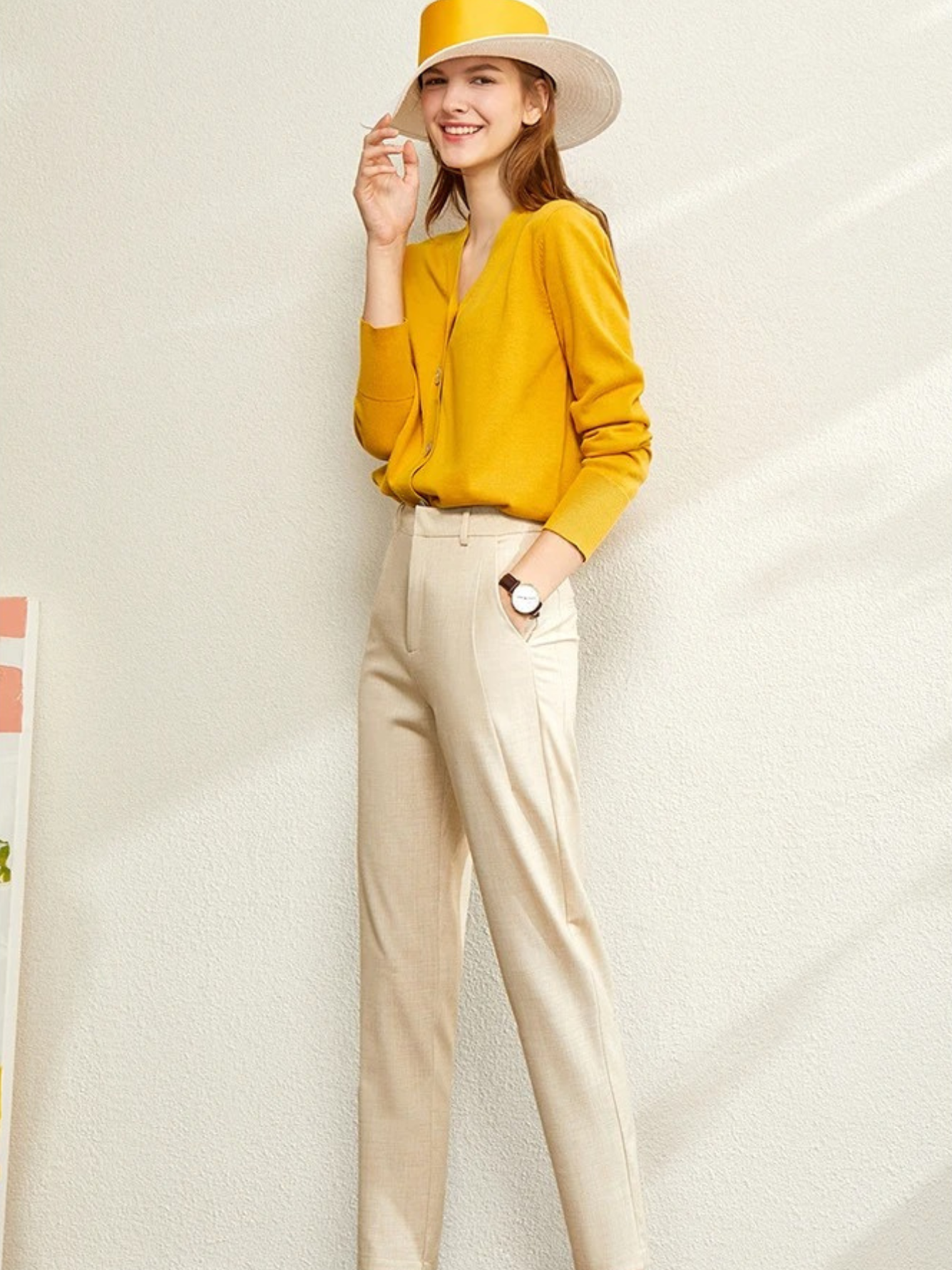 Model in mustard yellow cardigan and light beige trousers