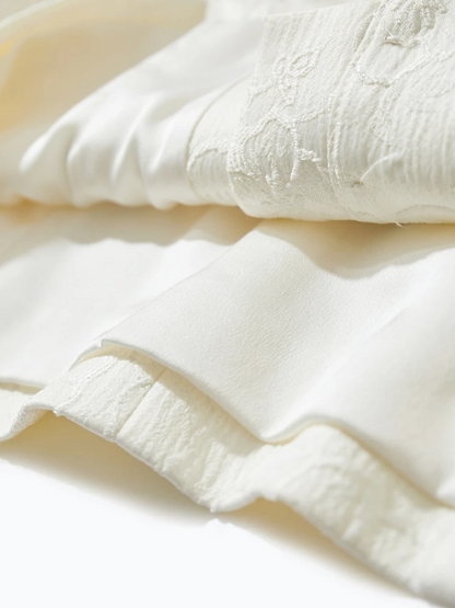 Fabric detail of cream blouse showing buttoned cuffs and texture