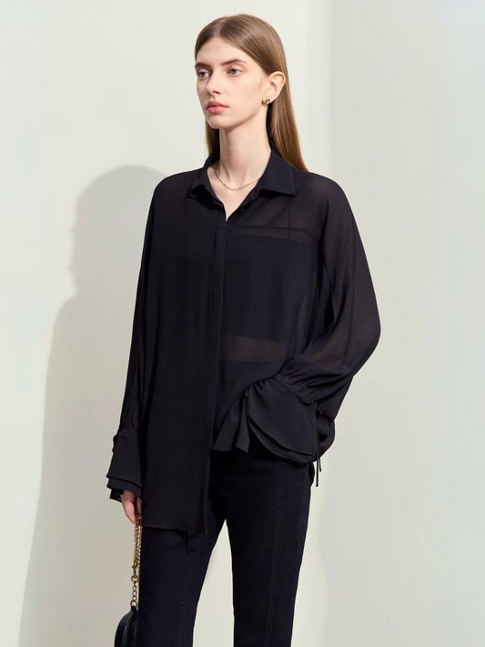 Woman wearing black sheer blouse with long sleeves and collar