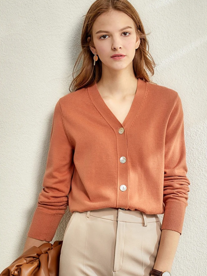 Woman in rust-coloured V-neck cardigan with beige trousers