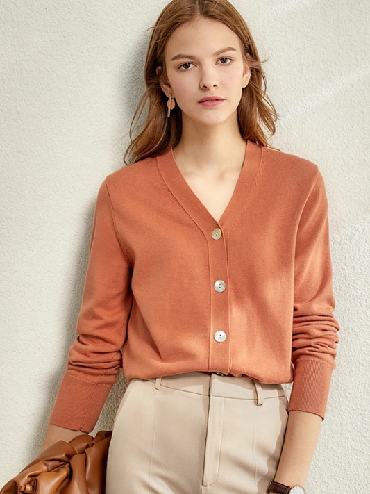 Woman in rust-coloured V-neck cardigan with beige trousers