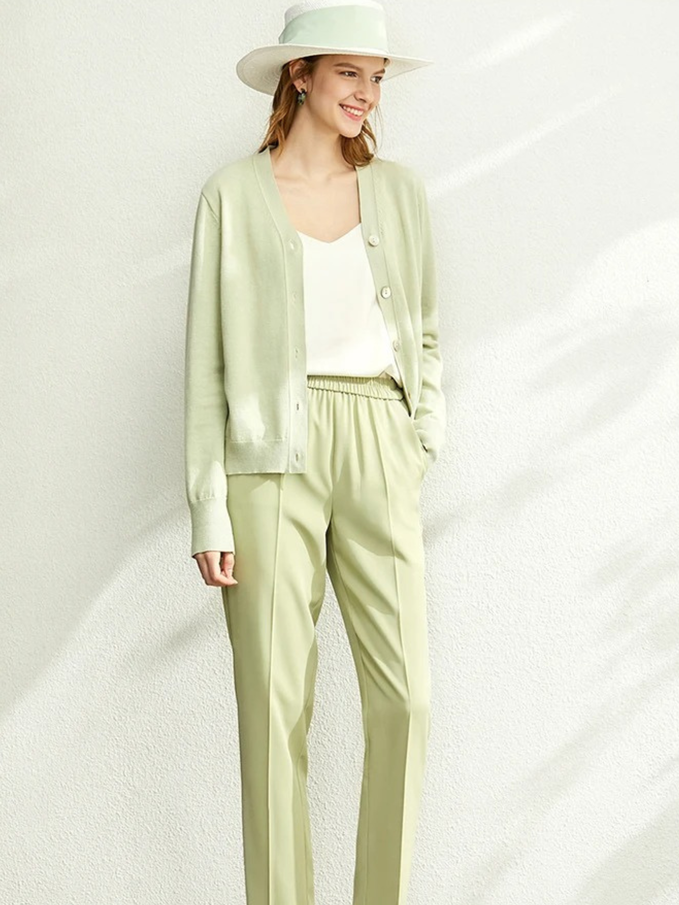Woman in light green cardigan and matching trousers with hat