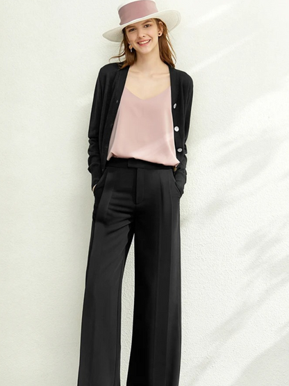 Woman in black cardigan over pink top and black trousers with hat

