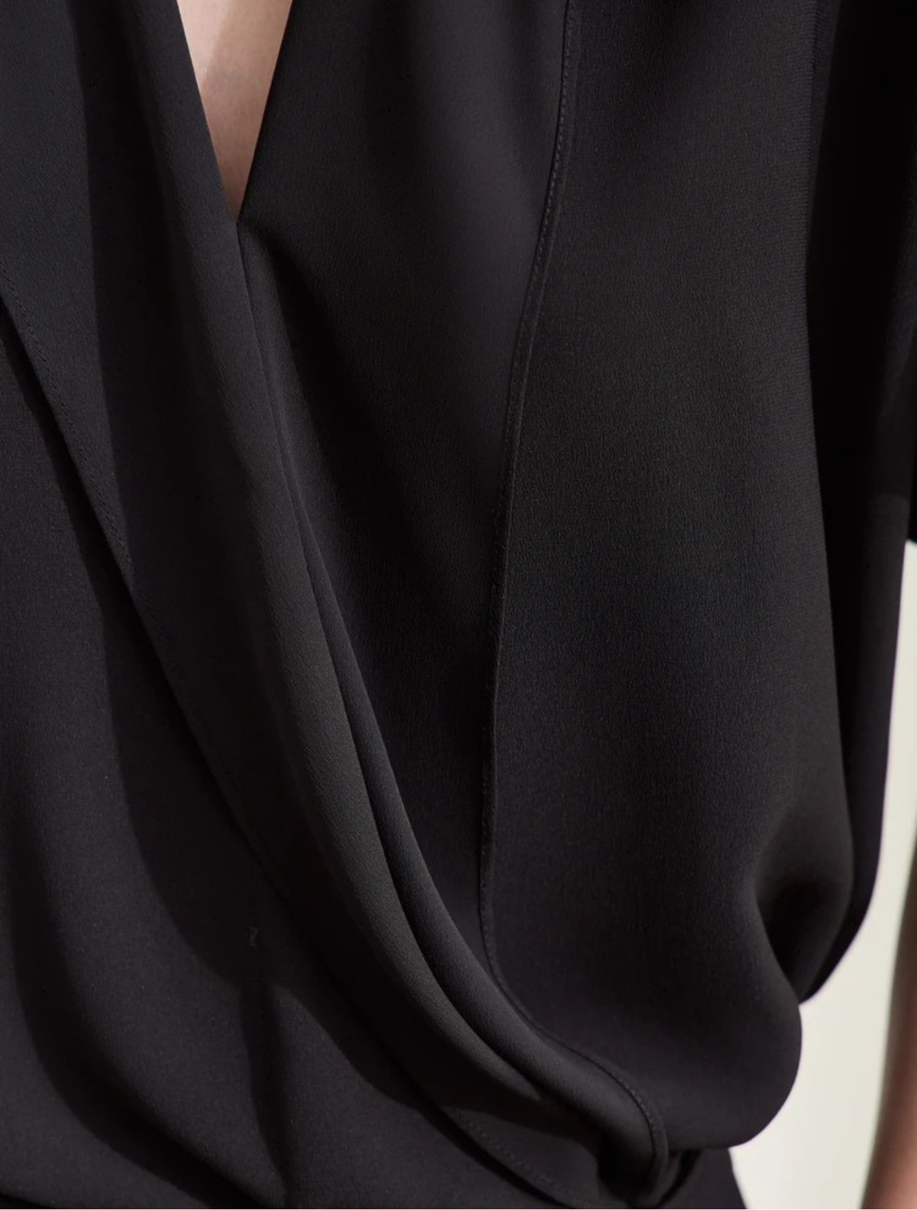 Woman in black blouse with hands in pockets and heels