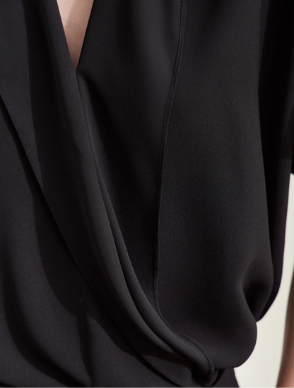 Woman in black blouse with hands in pockets and heels