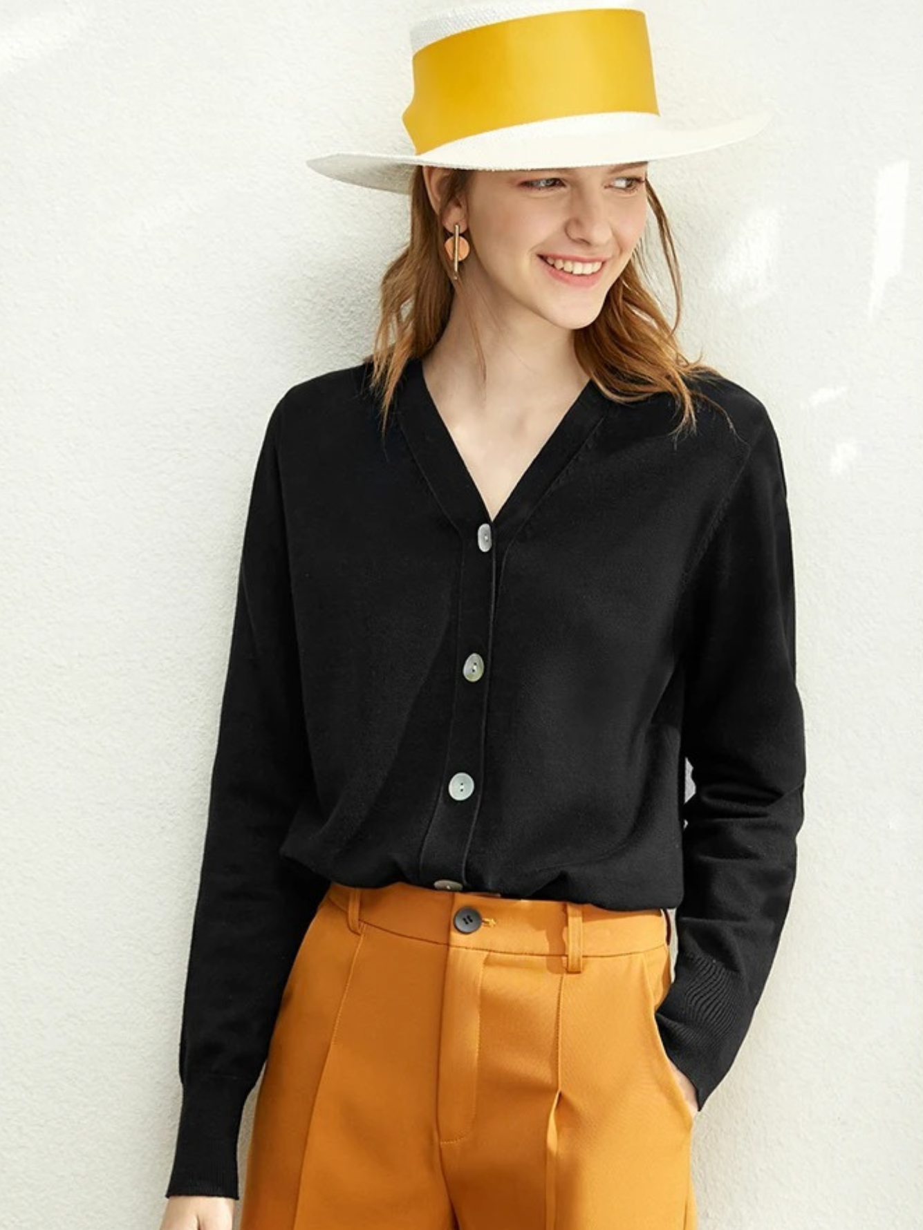 Woman in black cardigan and mustard trousers with yellow hat