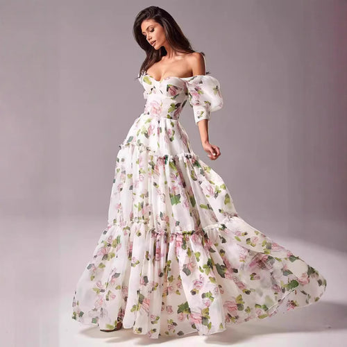 Kvinnens elegante maxikjole med avskåret skuldre, volangermiddels og blomsteracenter
