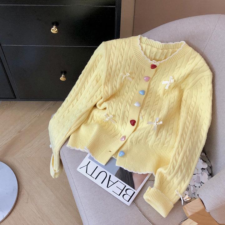 Kvinnens chunky strikket cardigan med lekne knappdetaljer og sløyfer