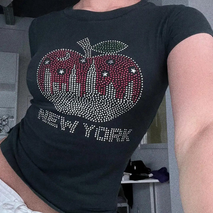 Dame stilig T-skjorte med glitrende eple-design og New York skrifttype Skjora
