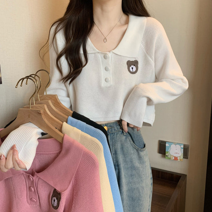 Kvinne cropped genser med en knapp lukking og unicorn emblem