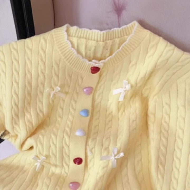Kvinnens chunky strikket cardigan med lekne knappdetaljer og sløyfer