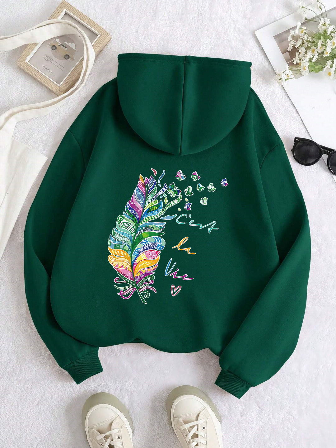 Dame avslappet hettegenser med fargerikt fjærdesign og inspirerende tekst Skjora