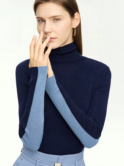 A woman wearing a dual toned dark blue and light blue turtleneck sweater that is interchangeable to achieve two looks.
