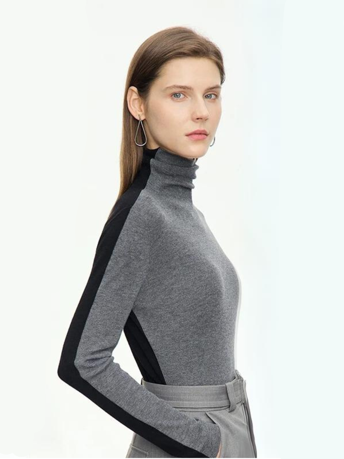 A woman wearing a dual toned black and gray turtleneck sweater that is interchangeable to achieve two looks.